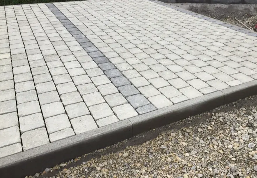 Betonpflaster mit dunklem Band, seitlich gefasst von einem Betonbord