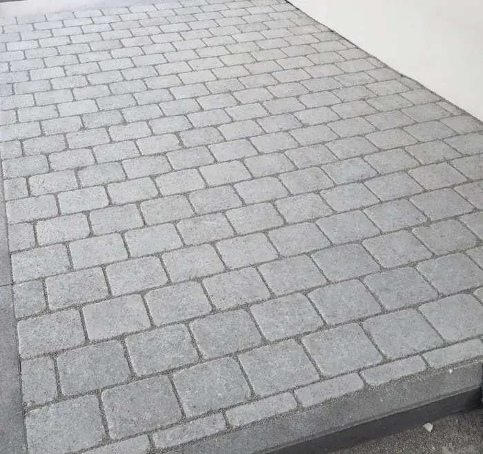 Helles Betonpflaster im Reihenverband vor einem Hauseingang