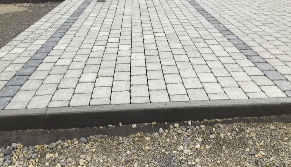 Neue Hofeinfahrt aus hellem Betonpflaster mit zwei anthrazitfarbenen Bändern und Randeinfassung