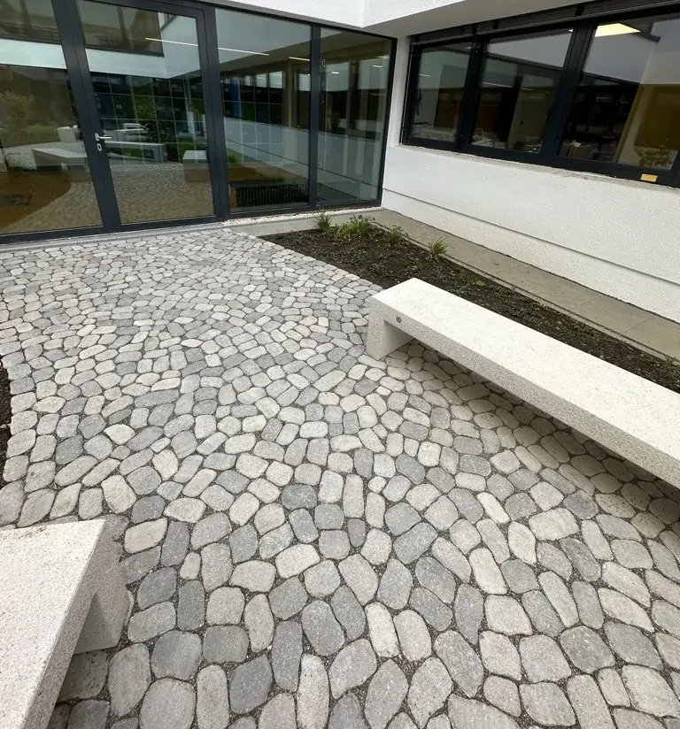 Betonpflaster ARENA mit runden Kanten und eine weiße Sitzbank im Innenhof