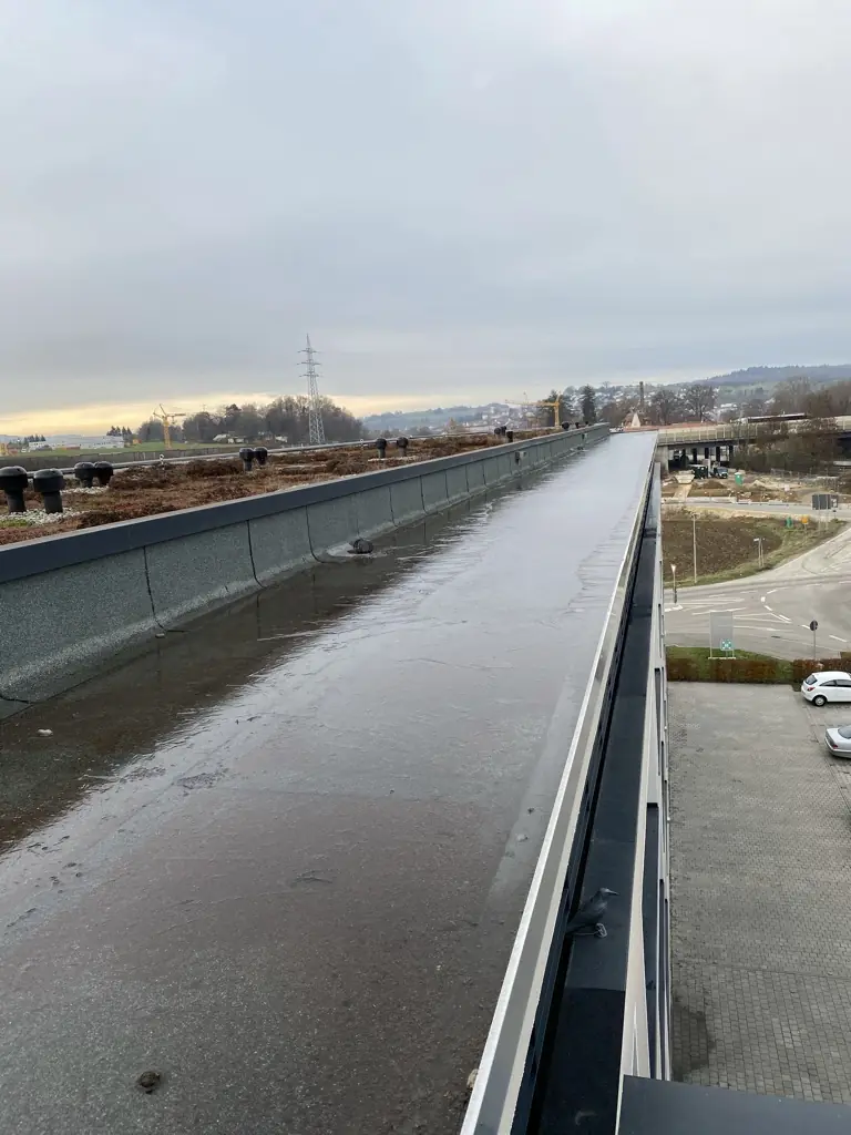 Großes Flachdach eines Gewerbegebäudes mit extensiver Begrünung im Winter, Dachentlüftern und einem Randstreifen an der Attika