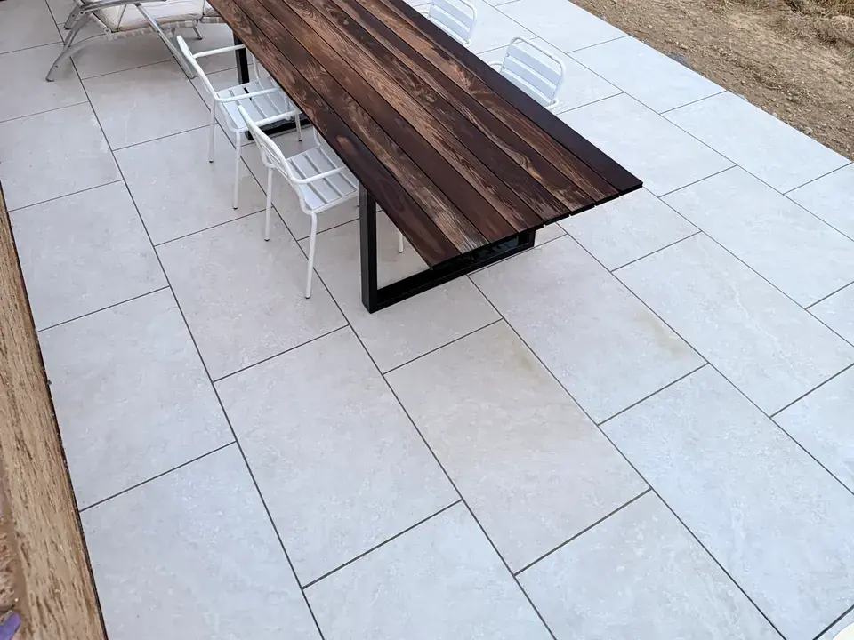 Fertige Terrasse aus großformatiger heller Keramik mit Holztisch