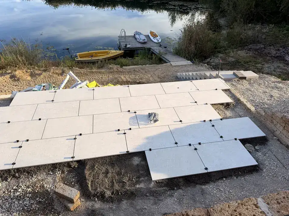 Verlegte Keramikplatten mit Nivelliersystem, im Hintergrund der See mit Steg