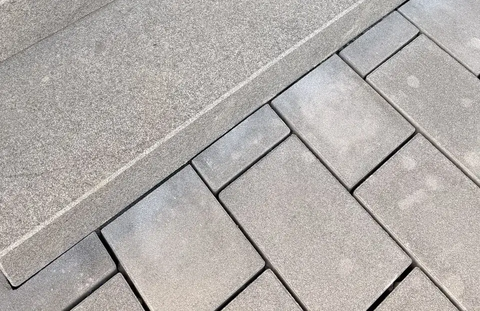 Blockstufe aus anthrazitfarbenem Granit mit sauberem Anschluss an graues Betonpflaster