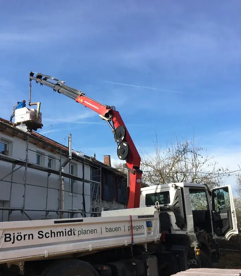 Kran-LKW hebt Material über das Gerüst aufs Dach