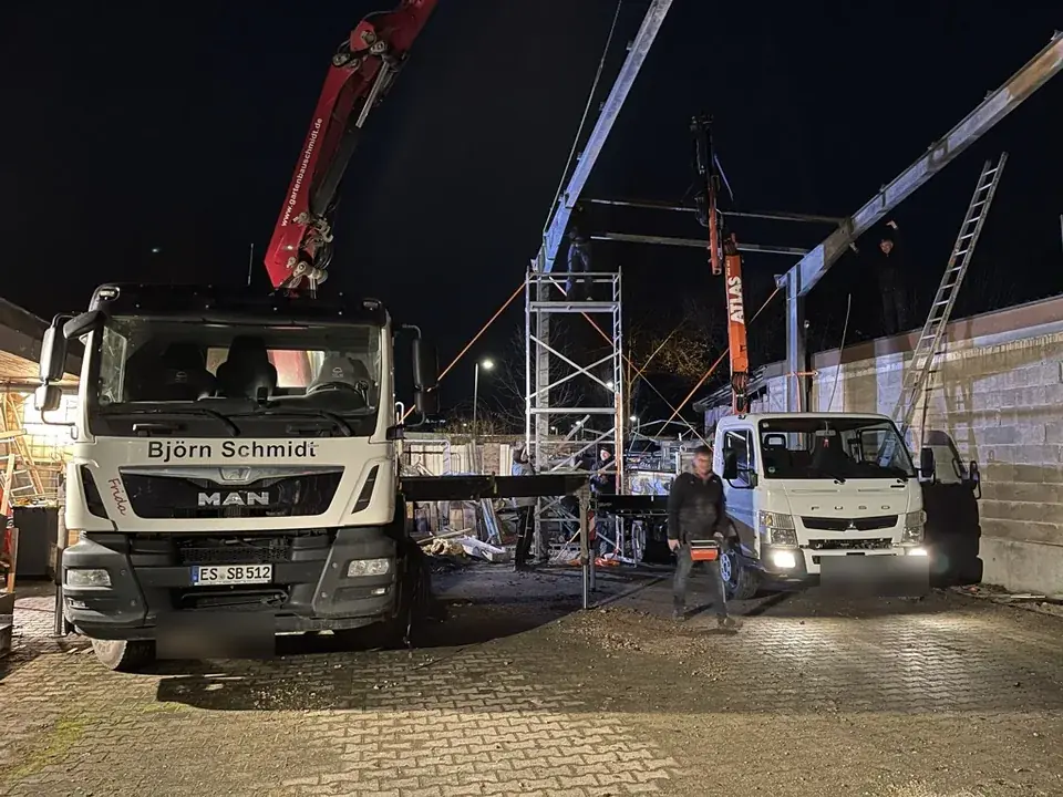 Kran-LKW und Transporter bei einem Einsatz am Abend vor einer Halle