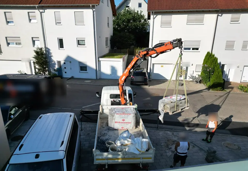 Kran-LKW hebt eine Palette mit Steinen von der Ladefläche