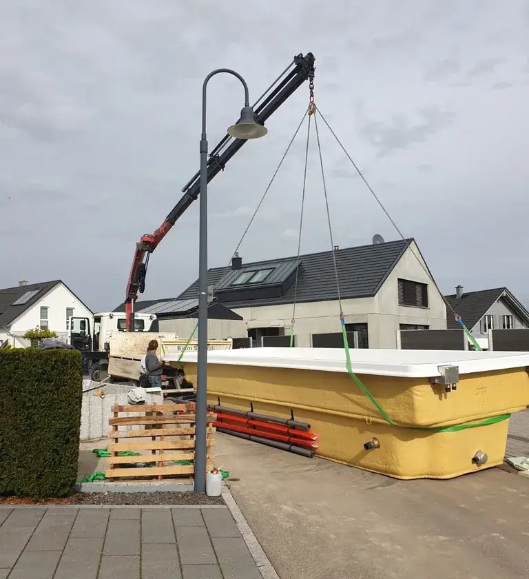 Kran setzt ein Fertigbecken auf der Straße ab
