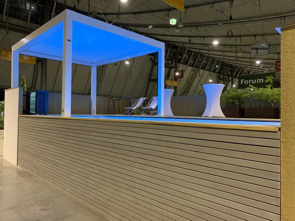 Pergola mit blauem Licht über dem Pool, Beckenverkleidung aus grauen Latten
