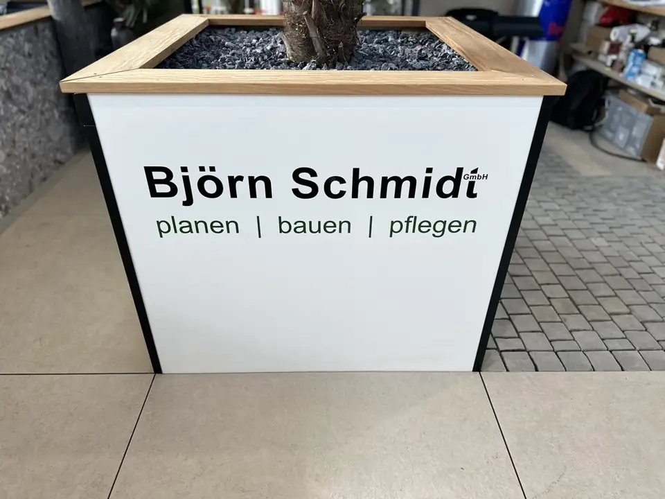 Pflanzkübel mit Holzrand und Logo Björn Schmidt planen bauen pflegen