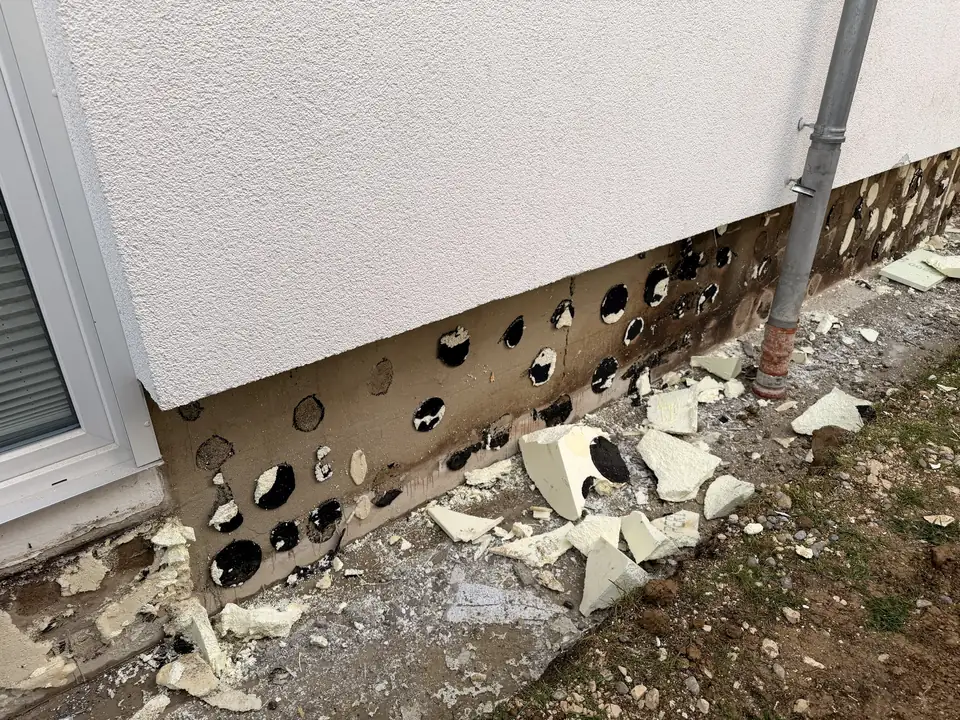 Sockel nach dem Entfernen der Dämmplatten, auf der Wand bleiben runde Klebepunkte zurück