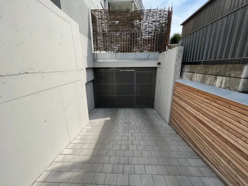Gepflasterte Tiefgaragenzufahrt vor einem Garagentor zwischen Betonwänden