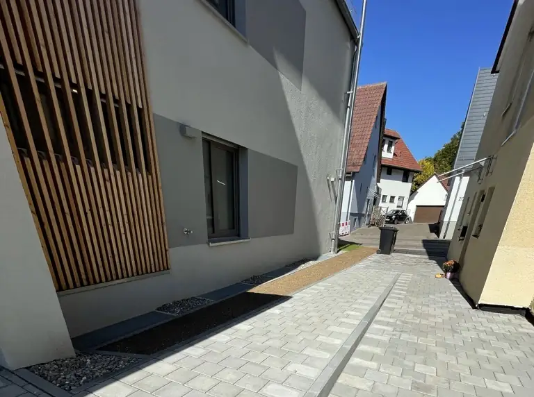 Weg an einer Wohnanlage aus Betonpflaster, daneben Stellplätze mit Rasenwaben